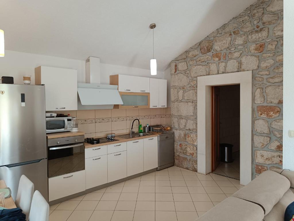 een keuken met witte kasten en een stenen muur bij Apartment Nada in Rogoznica