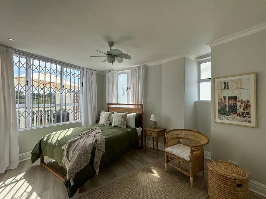 ein Schlafzimmer mit einem Bett, einem Fenster und einem Stuhl in der Unterkunft High tide at no 16 in St Francis Bay