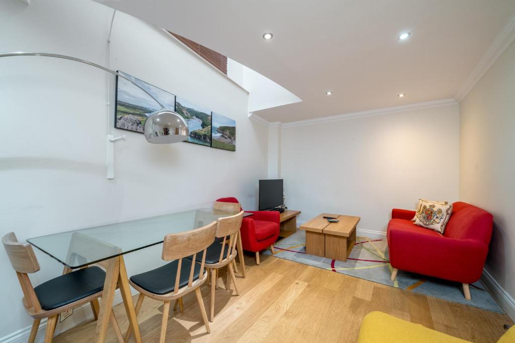 - un salon avec une table en verre et des chaises rouges dans l'établissement Great flat near St Paul’s Cathedral, à Londres
