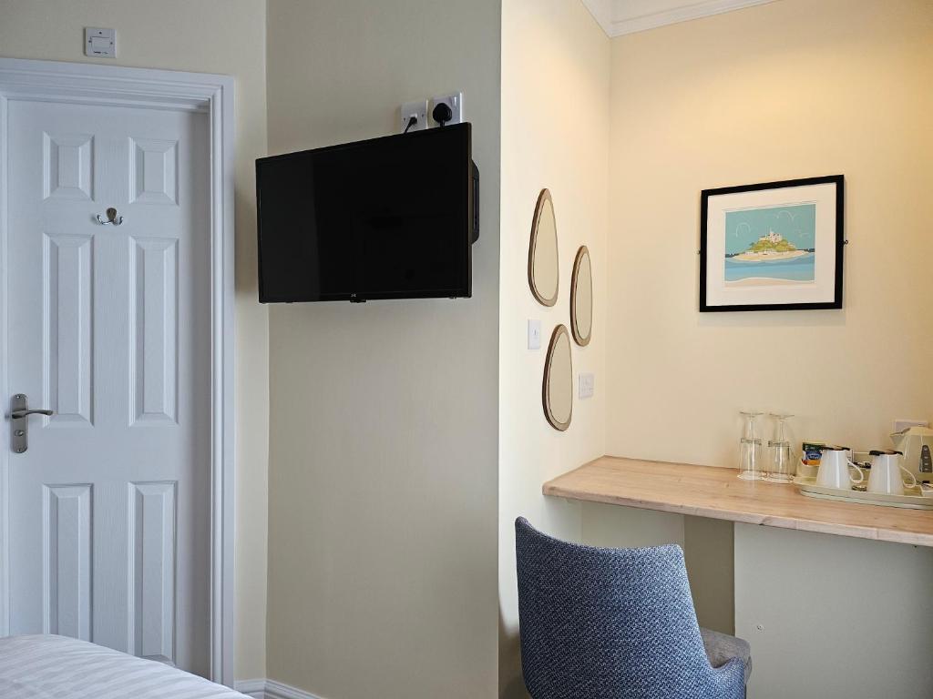 a bedroom with a tv on the wall and a blue chair at Geckos Rest in Newquay