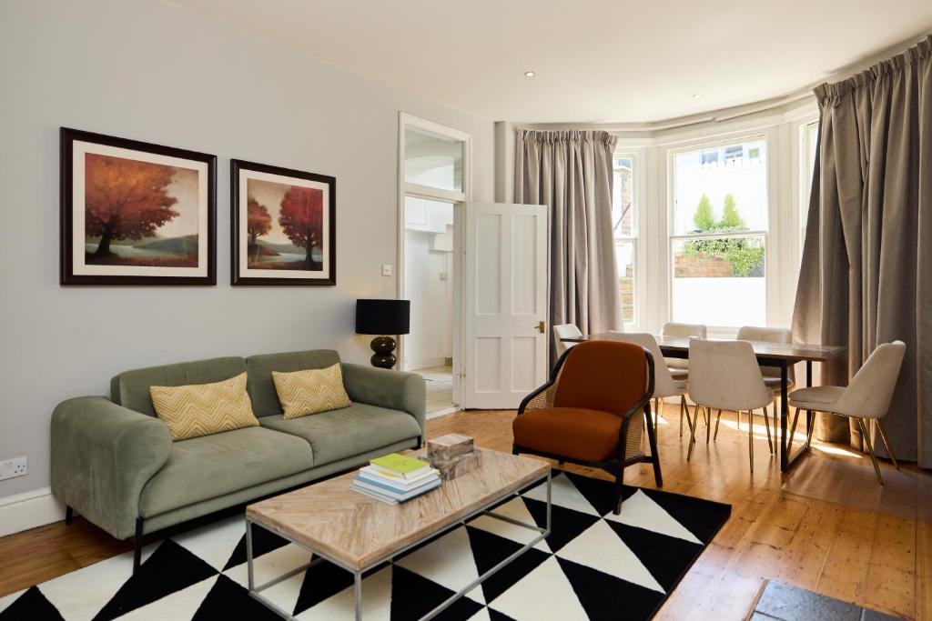 een woonkamer met een bank en een tafel bij The West Kensington Hideout - Cozy 2BDR Flat with Garden in Londen
