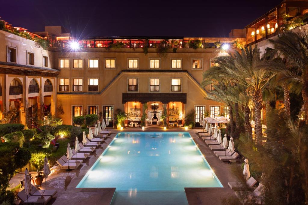 a pool in front of a building at night at Les Jardins De La Koutoubia in Marrakesh