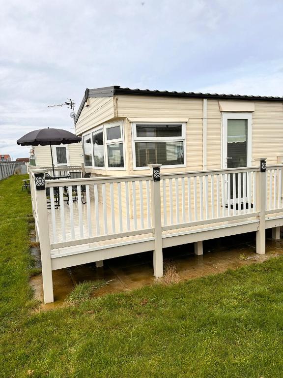 a mobile home with a white fence and an umbrella at Browns caravan rentals, ingoldmells 4 berth caravan silver beach in Ingoldmells