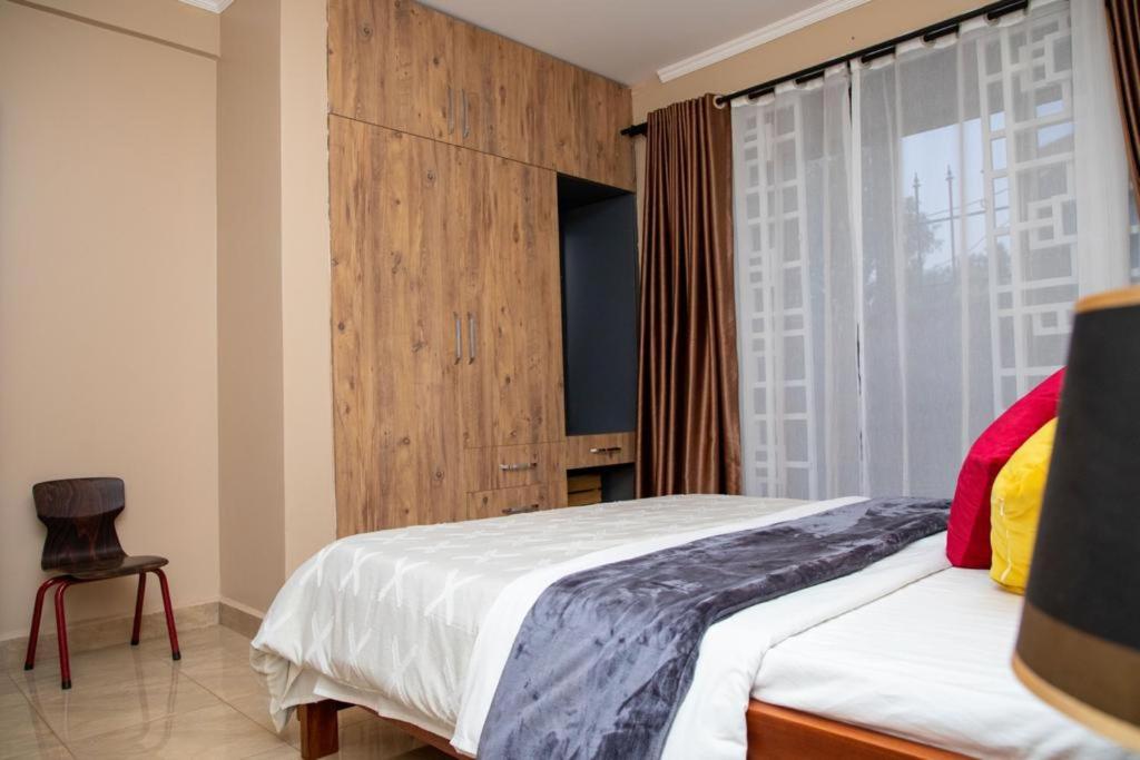 um quarto com uma cama, uma janela e uma cadeira em Olive homes em Kampala