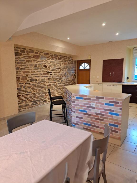 eine Küche mit einem Tisch und einer Ziegelwand in der Unterkunft Gite 3 chambres - proche canal - bretagne in Saint-Nicolas-de-Redon