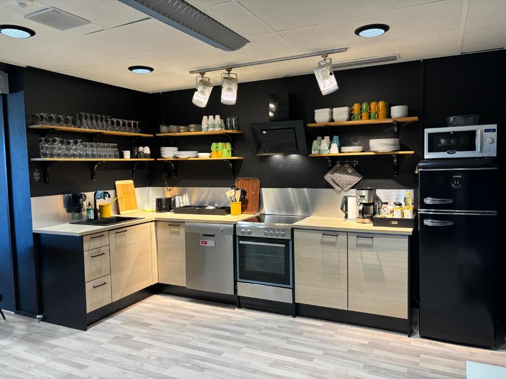 uma cozinha com paredes pretas e electrodomésticos de aço inoxidável em Hotelli Jämsä em Jämsä