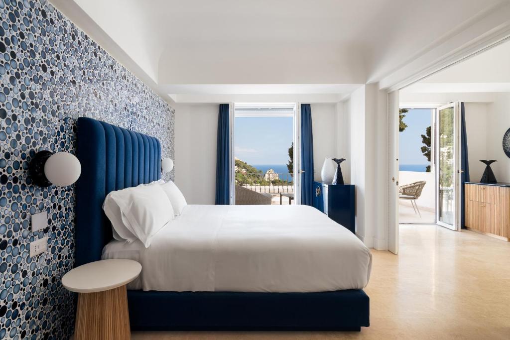 La Residenza Capri في كابري: غرفة نوم بسرير ابيض وجدار ازرق