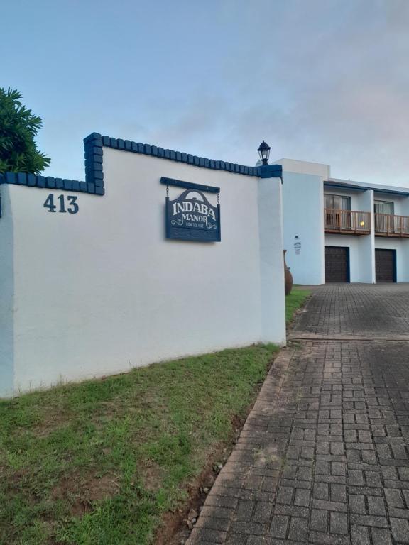 a white building with a sign on the side of it at Indaba Manor Guesthouse in Port Edward