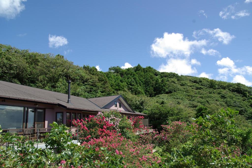 a house with a mountain in the background at Mashio Hotel & Resort in Oshima