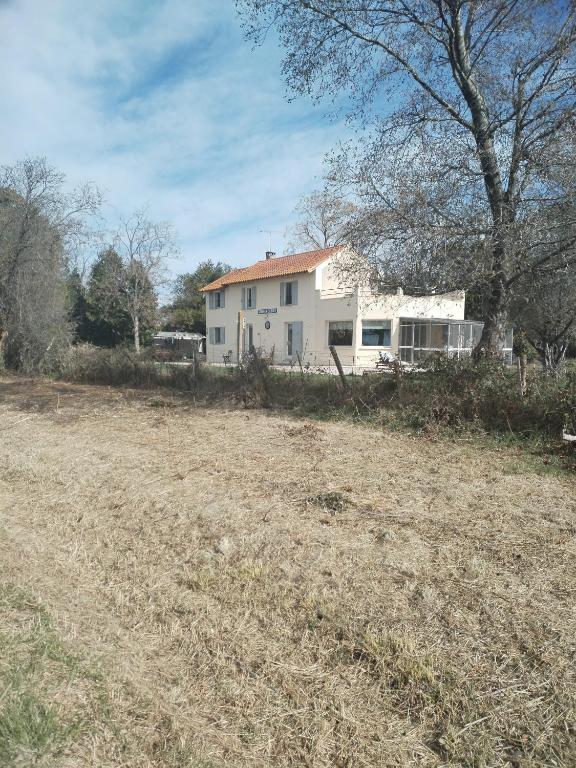 un champ vide devant une maison blanche dans l'établissement Ancienne Gare, à Arles