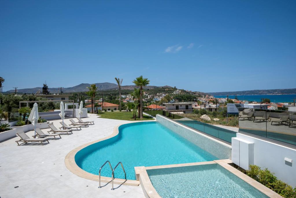 a large swimming pool with lounge chairs and the ocean at AmphiMatrion Luxury Apartments in Kalyves