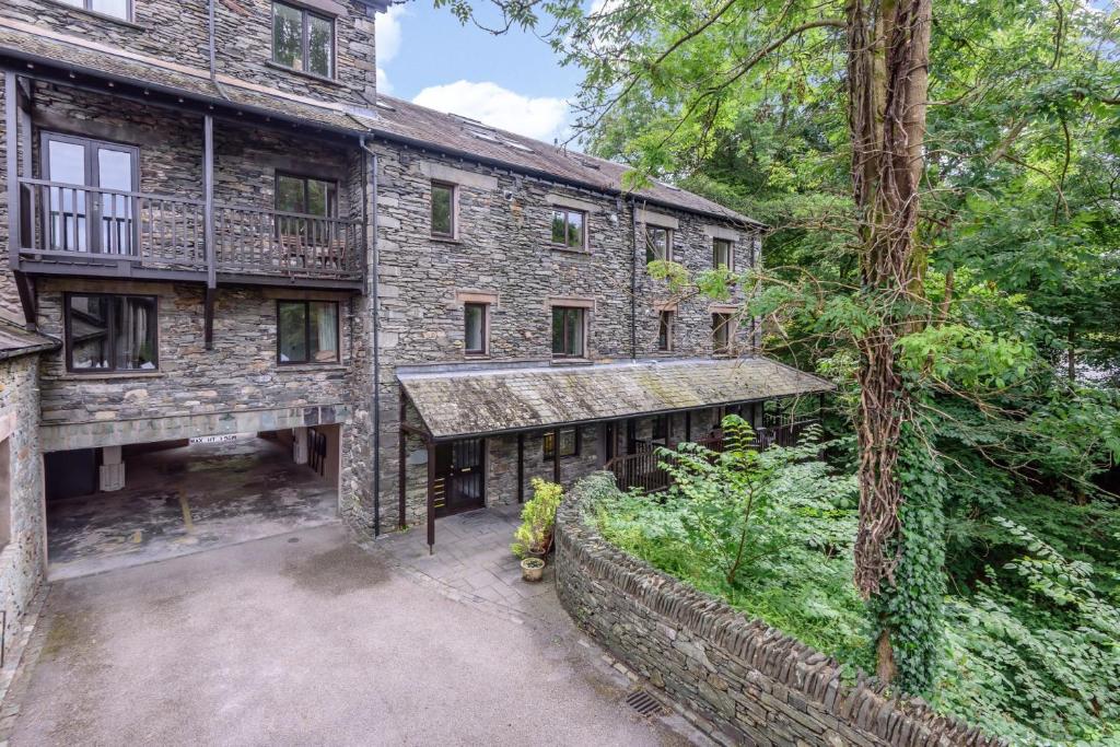 an exterior view of an old stone house with a garden at Mill Top in Ambleside