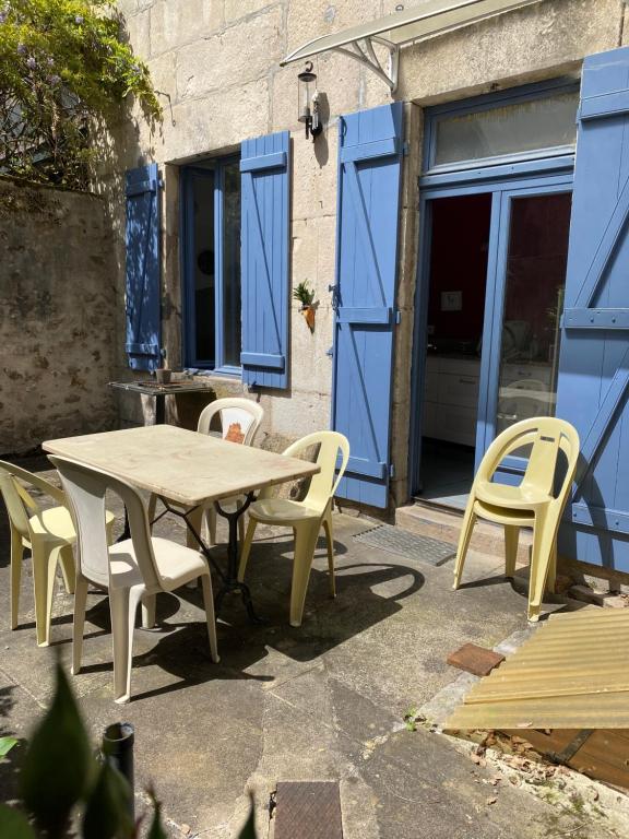 une table et des chaises devant un bâtiment avec des portes bleues dans l'établissement Maison de l horloge, à Avallon