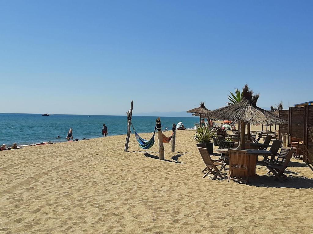 une plage avec des chaises et des hamacs et l'océan dans l'établissement Les Pieds dans l'Eau, au Barcarès