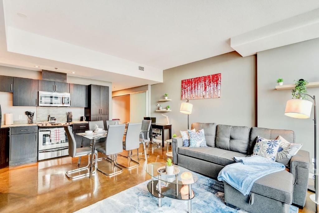 ein Wohnzimmer mit einem Sofa und einem Tisch in der Unterkunft Modern 2BR Condo - King Bed - Downtown City Views in Calgary