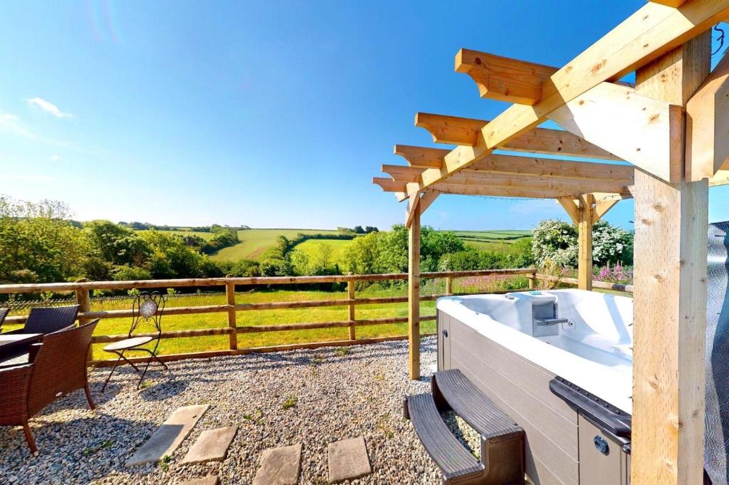 a wooden pergola with a bath tub on a patio at Georgeham Sweet Pea Cottage in Georgeham