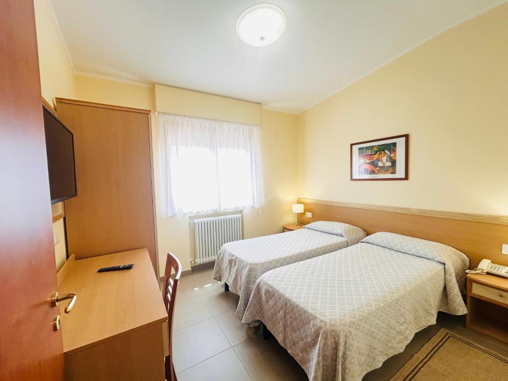 a hotel room with two beds and a television at Il Nocchiero City Hotel in Soverato Marina