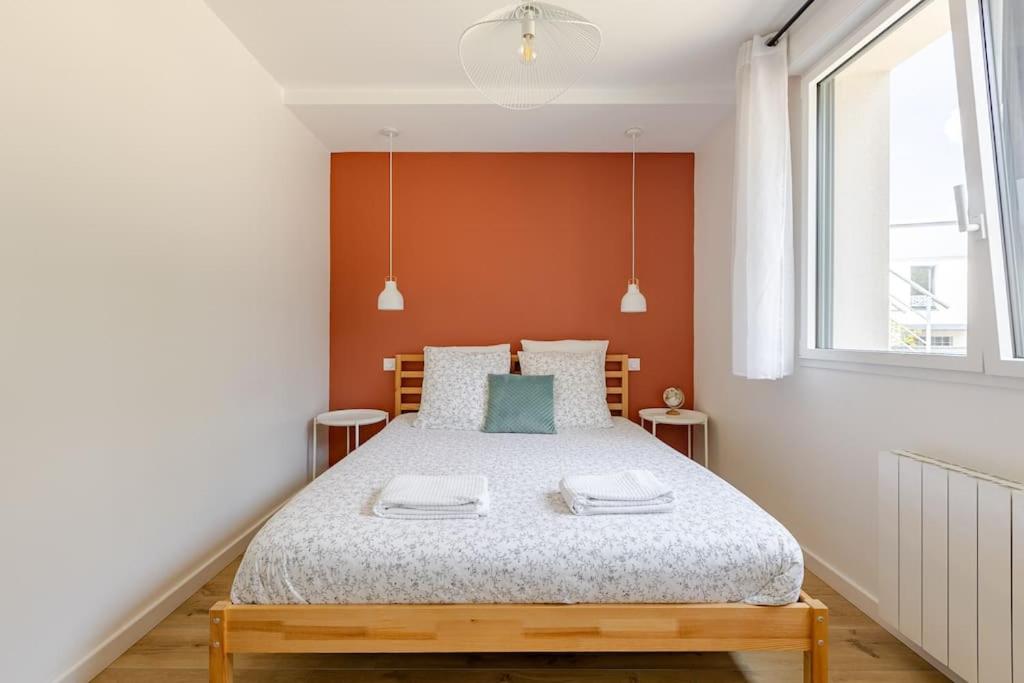 a bedroom with a bed with orange walls and a window at Ar Mor, votre pied à terre cocoon au cœur de ville in Paimpol