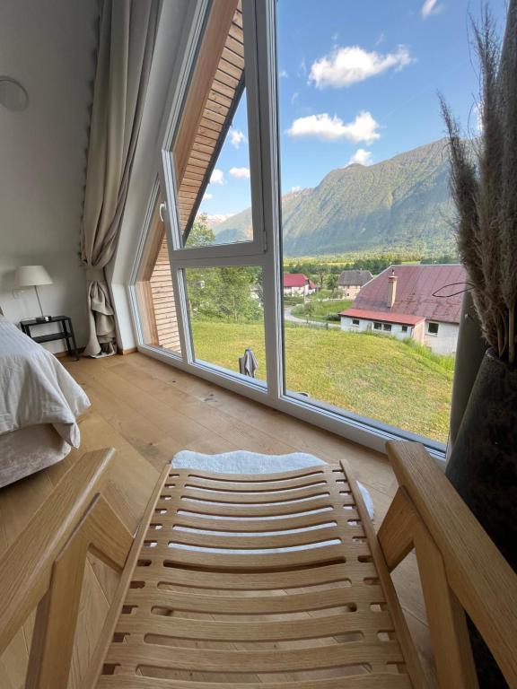 ein Schlafzimmer mit einem großen Fenster, einem Bett und einem Stuhl in der Unterkunft The Valley Queens in Bovec