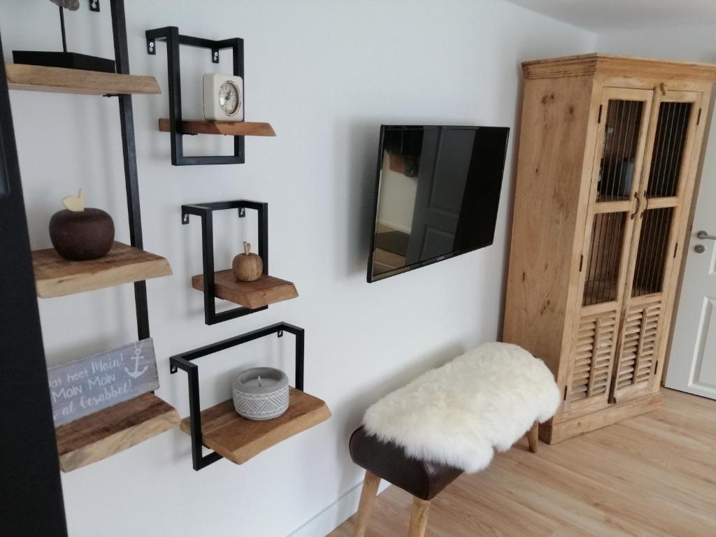 a room with wooden shelves and a stool and a tv at Kapitänsliebe in Upleward