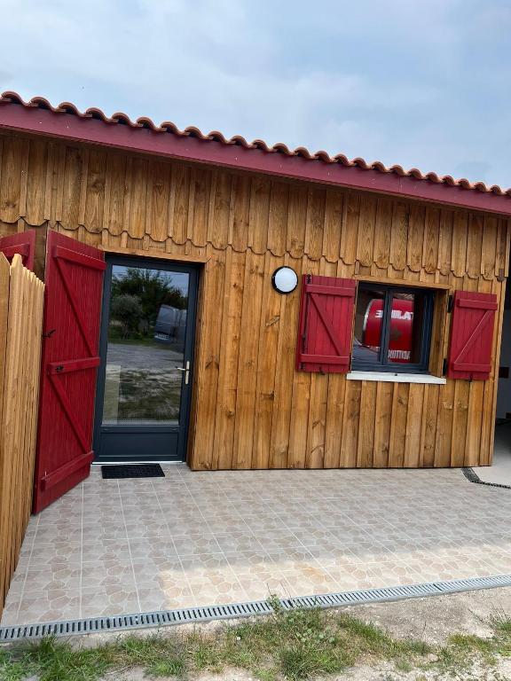 - un bâtiment en bois avec des portes et des fenêtres rouges dans l'établissement eco nature, gite à la ferme, à Vendays-Montalivet