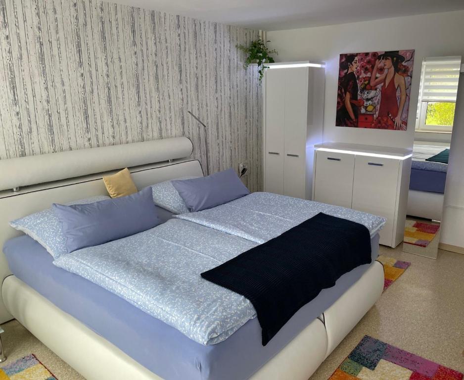 a bedroom with a white bed with blue pillows at Ferienwohnung am Rennsteig bei Eisenach - Ilona Schmidt in Wolfsburg-Unkeroda