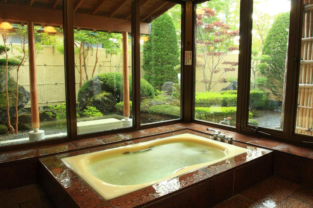 a bath tub in a room with a window at Yabukiso in Yamanakako
