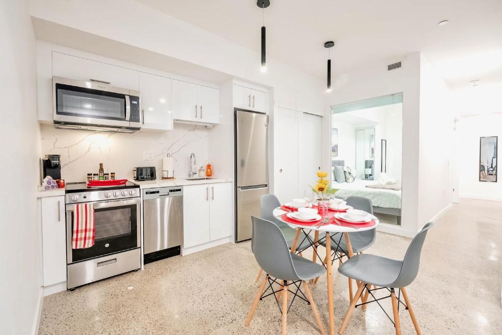 a white kitchen with a table and chairs in it at Stylish 2BR Condo in Proximity to City Center in Toronto