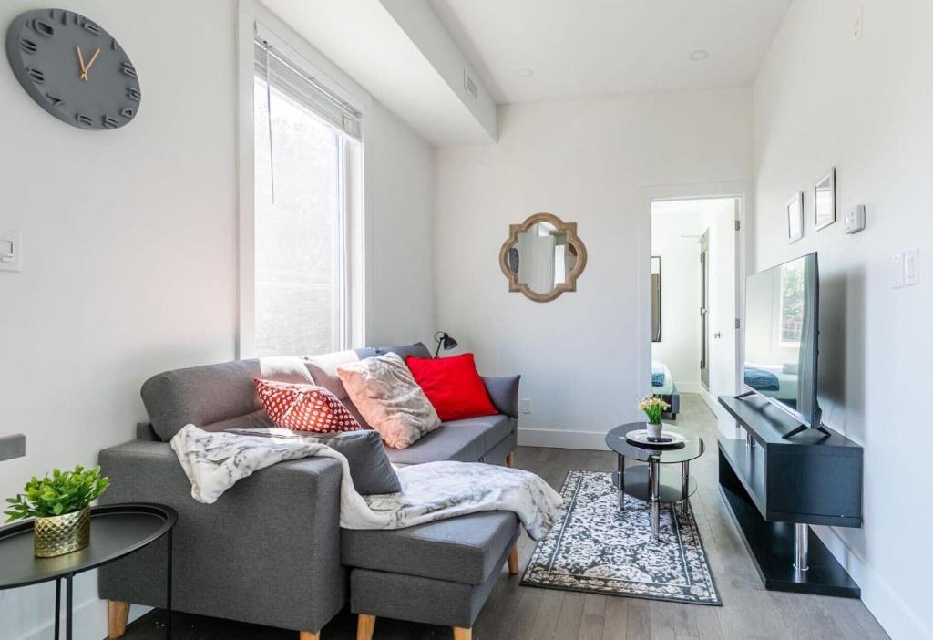 a living room with a couch and a clock on the wall at Spacious 2BR Apartment - Minutes to Leslieville in Toronto