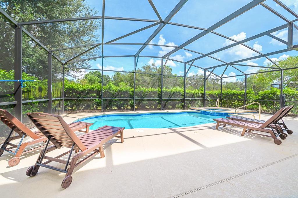 a swimming pool with two chairs and a glass roof at Solterra Resort Home - Waterslide and Lazy River in Davenport