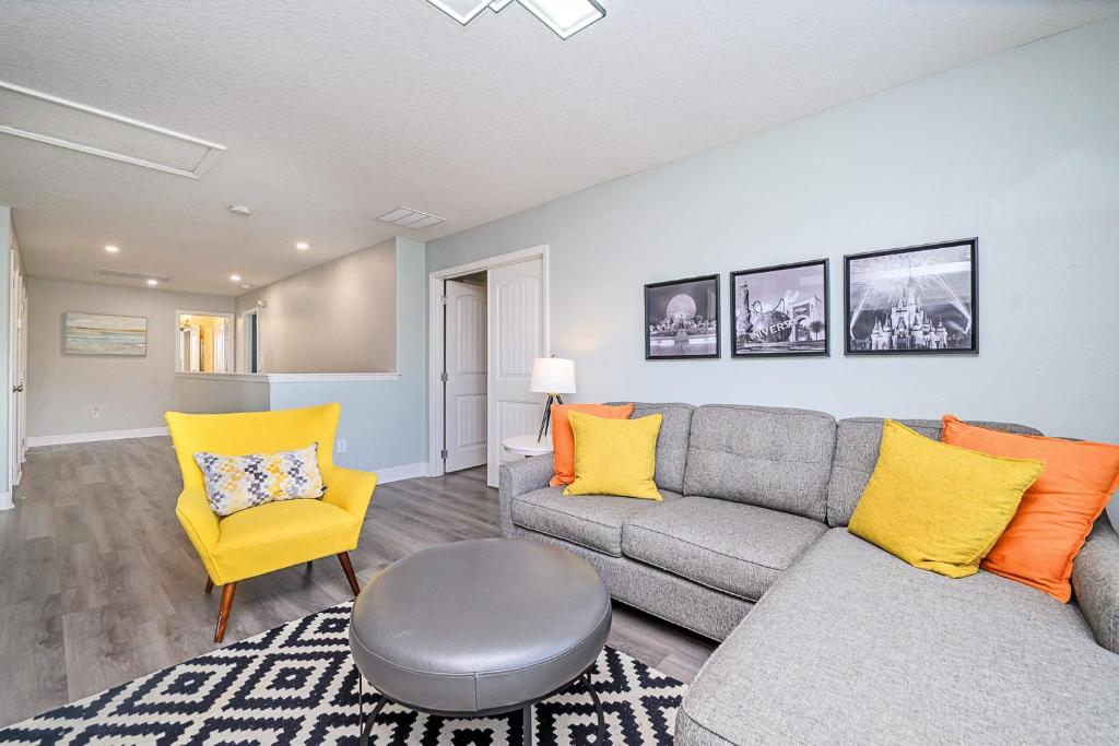 a living room with a gray couch and yellow chairs at Solterra Resort Home - Waterslide and Lazy River in Davenport