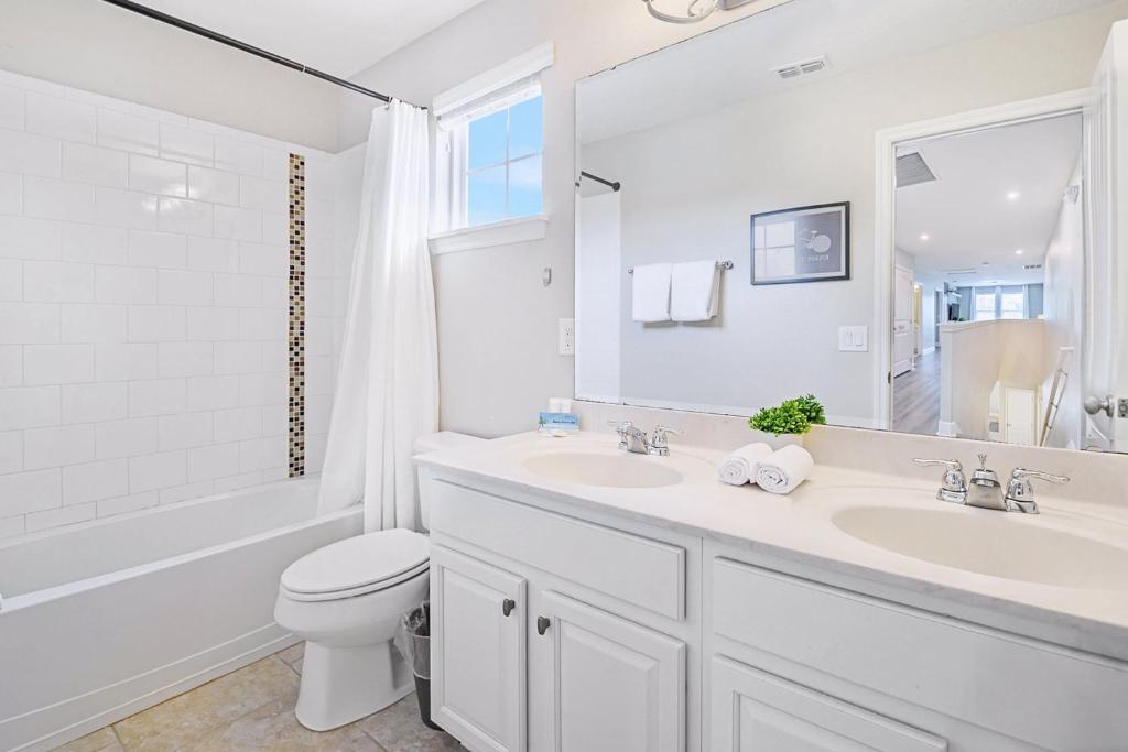 a white bathroom with a sink and a toilet at Solterra Resort Home - Waterslide and Lazy River in Davenport