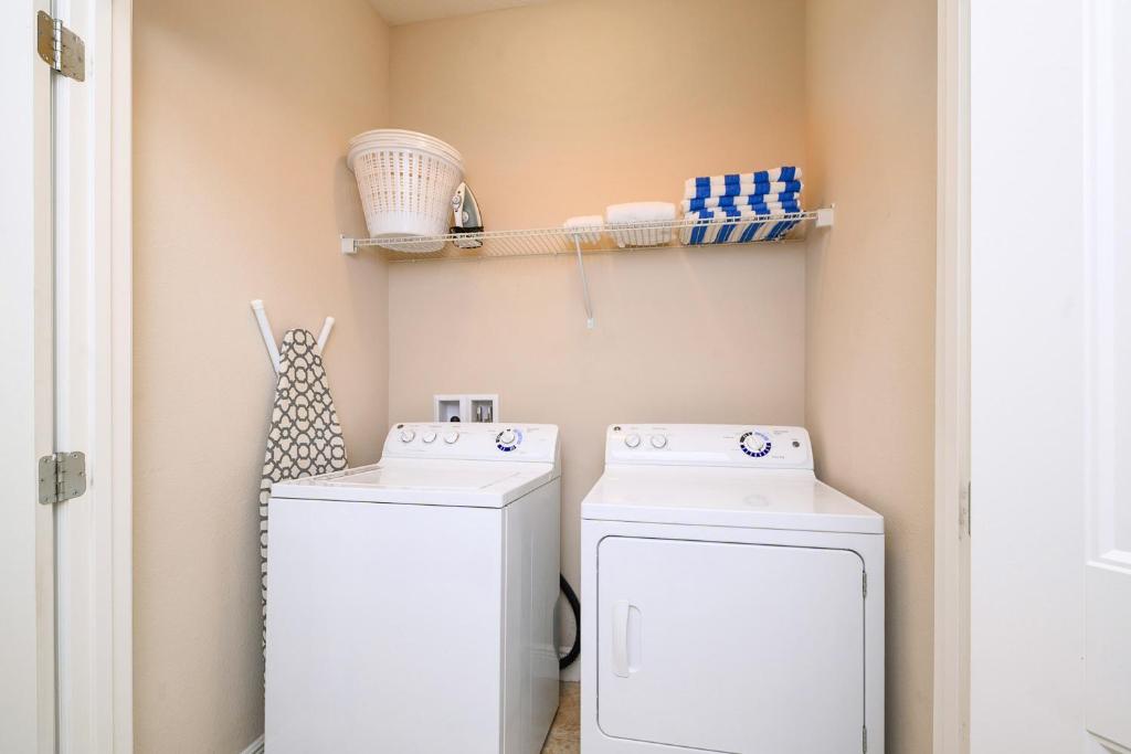 a laundry room with two washing machines and shelves at Solterra Resort Home - Waterslide and Lazy River in Davenport