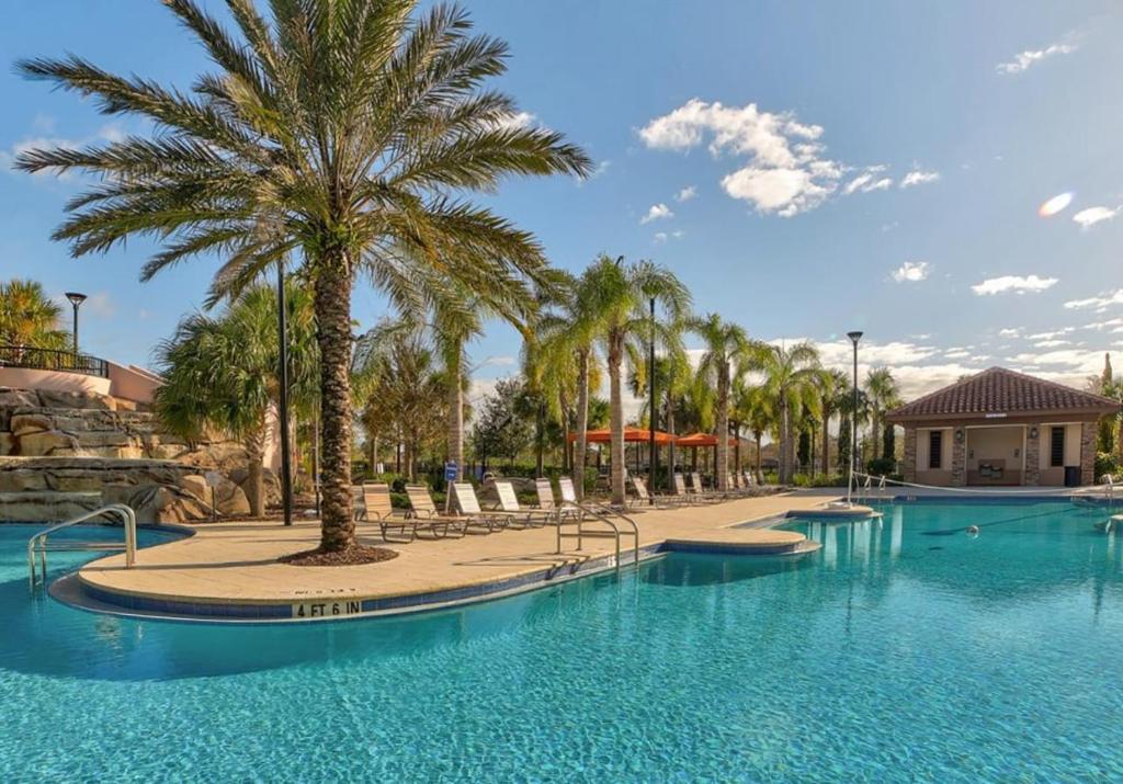 a large swimming pool with palm trees in a resort at Solterra Resort Home - Waterslide and Lazy River in Davenport