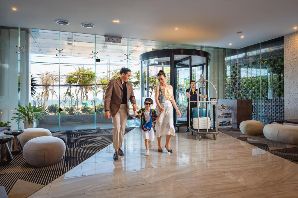 a family walking down a hallway in a hotel lobby at Premier Pearl Hotel Vung Tau in Vung Tau