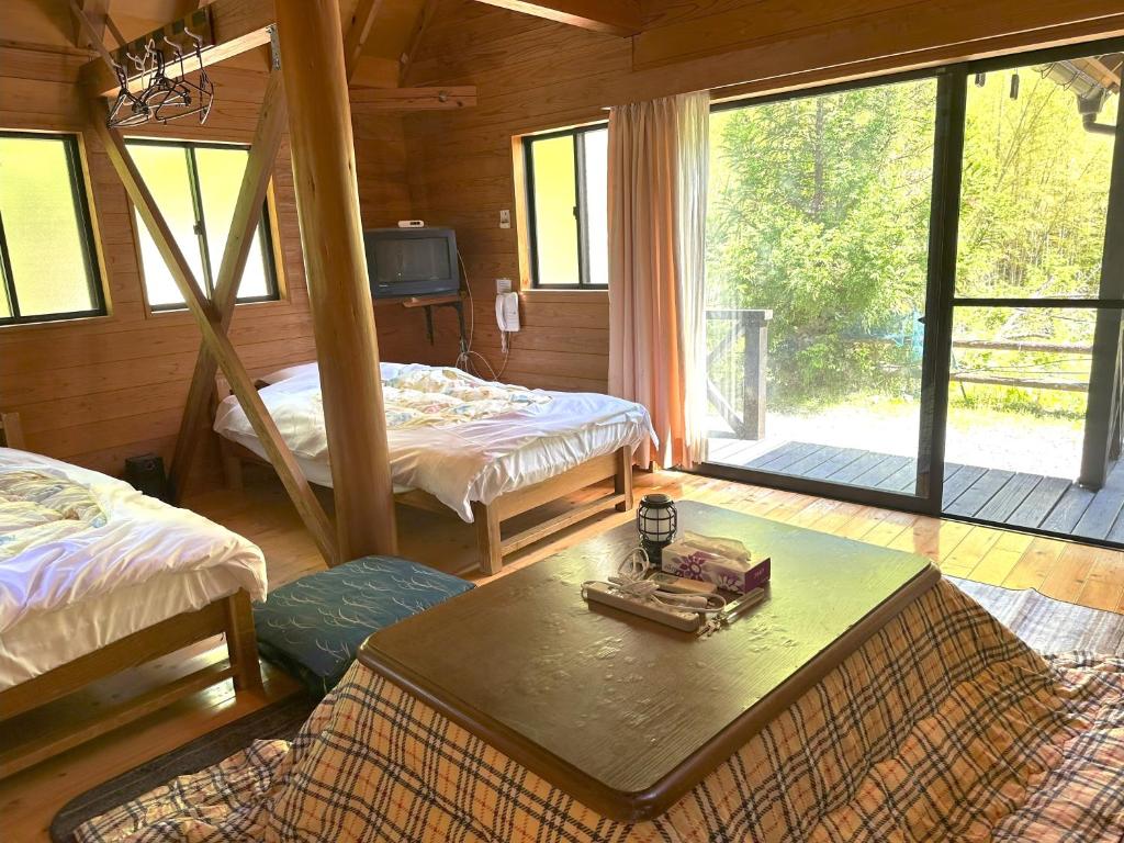 a room with two beds and a table and a tv at MARUTA 和歌山すさみ in Susami