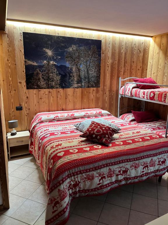 a bedroom with two beds and a painting on the wall at Residenze Vezza - La Corteccia- in Vezza dʼOglio