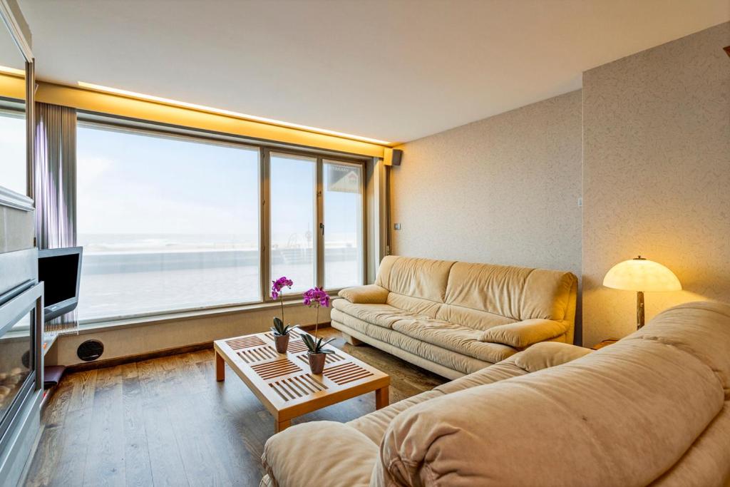 a living room with two couches and a large window at Rembrandt Glv in Wenduine