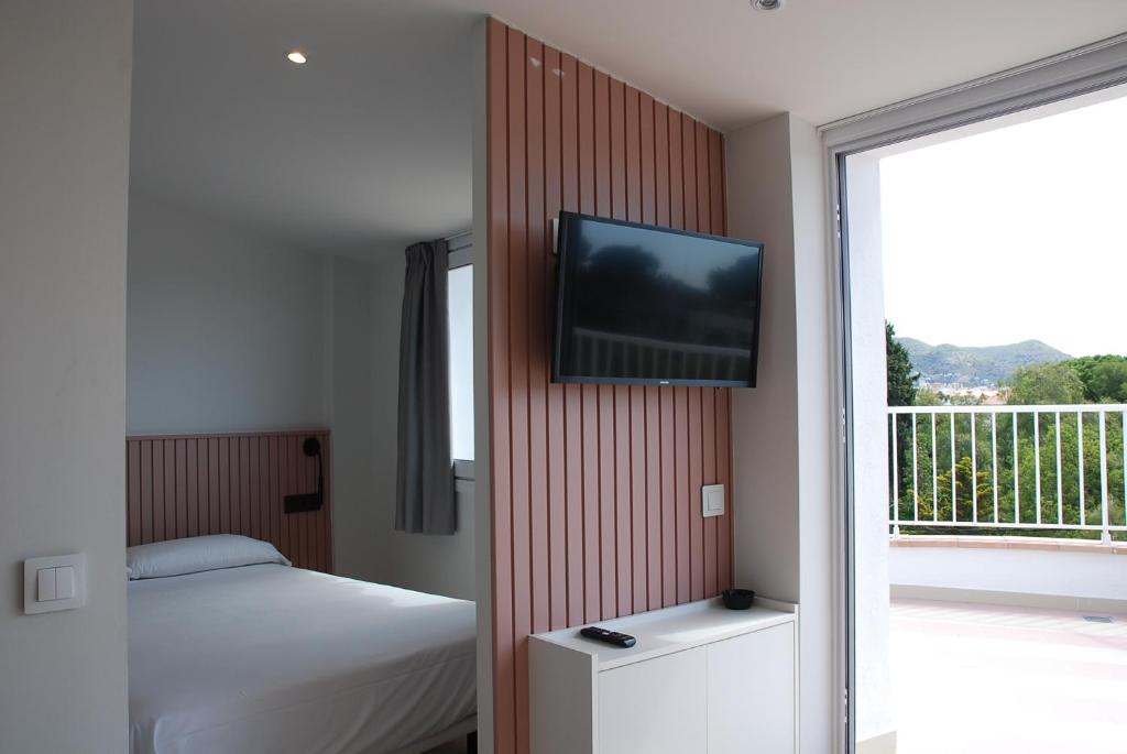 a bedroom with a bed and a television on a wall at Apartamentos Sunway Atlanta in Sitges