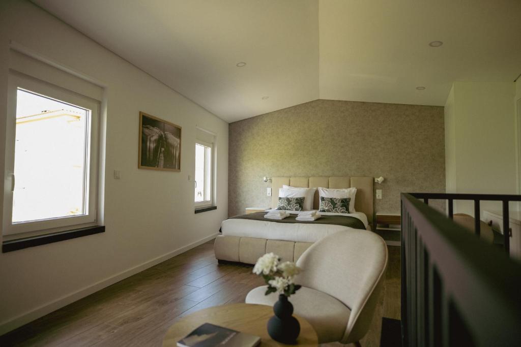 a bedroom with a bed and a chair and a table at Casa da Adega in Vila Nova de Foz Coa