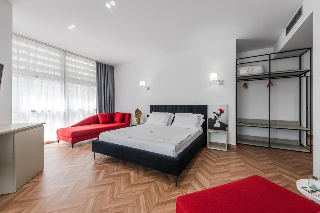 a bedroom with a bed and a red couch at Polifonia City Loft - Hotel rooms Vlorë, Albania in Vlorë