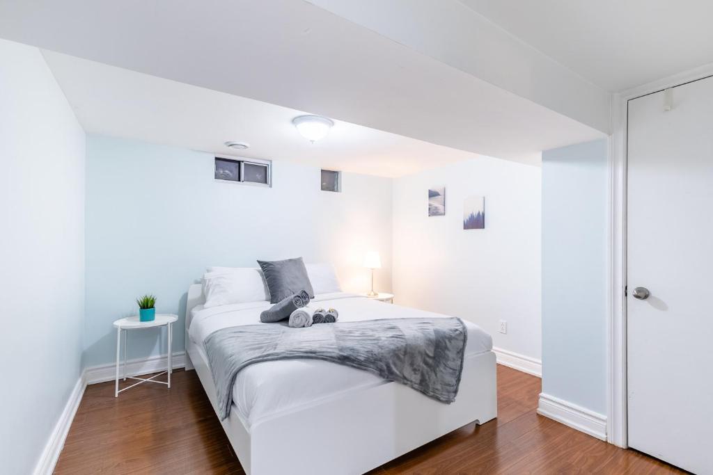 a white bedroom with a bed and a table at 2 Bedroom Apartment in the Heart of Trinity Bellwoods in Toronto
