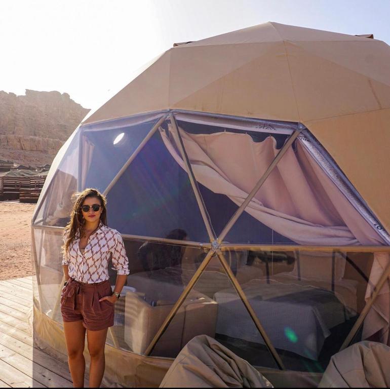uma mulher em pé em frente a uma tenda em RUM MAGiC lUXURY CAMP em Wadi Rum