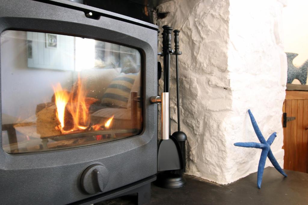 ein Herd mit einem Feuer darin und einem Seestern in der Unterkunft Little Gem in the Mumbles! Fishermans Cottage with Log Burner, Dog friendly and Welcome Breakfast Hamper! in The Mumbles