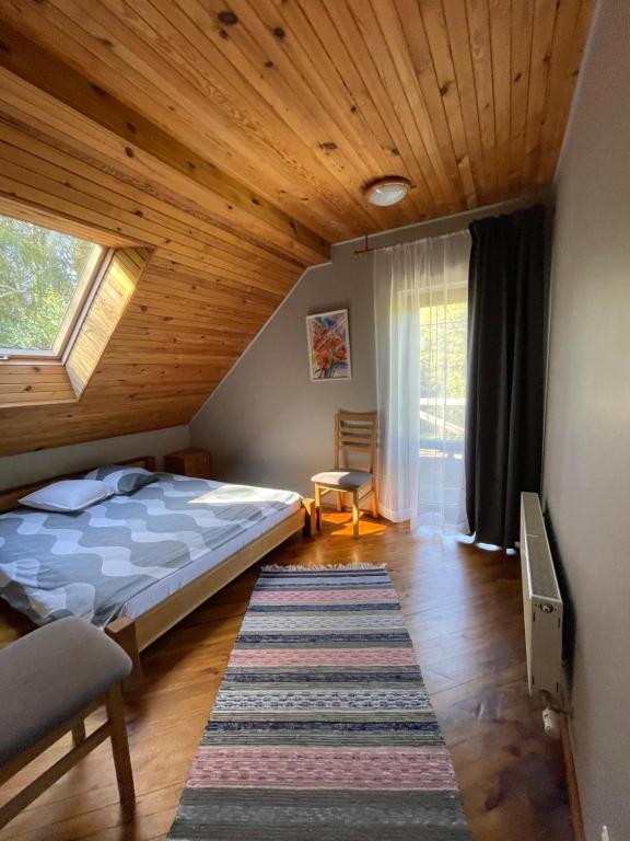 1 dormitorio con cama y techo de madera en Kārkli, en Kandava
