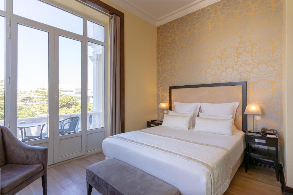 a bedroom with a bed and a window and a chair at Hotel Inglaterra - Charme & Boutique in Estoril
