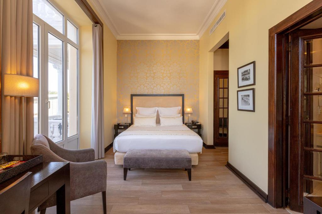a bedroom with a bed and a desk and a chair at Hotel Inglaterra - Charme & Boutique in Estoril