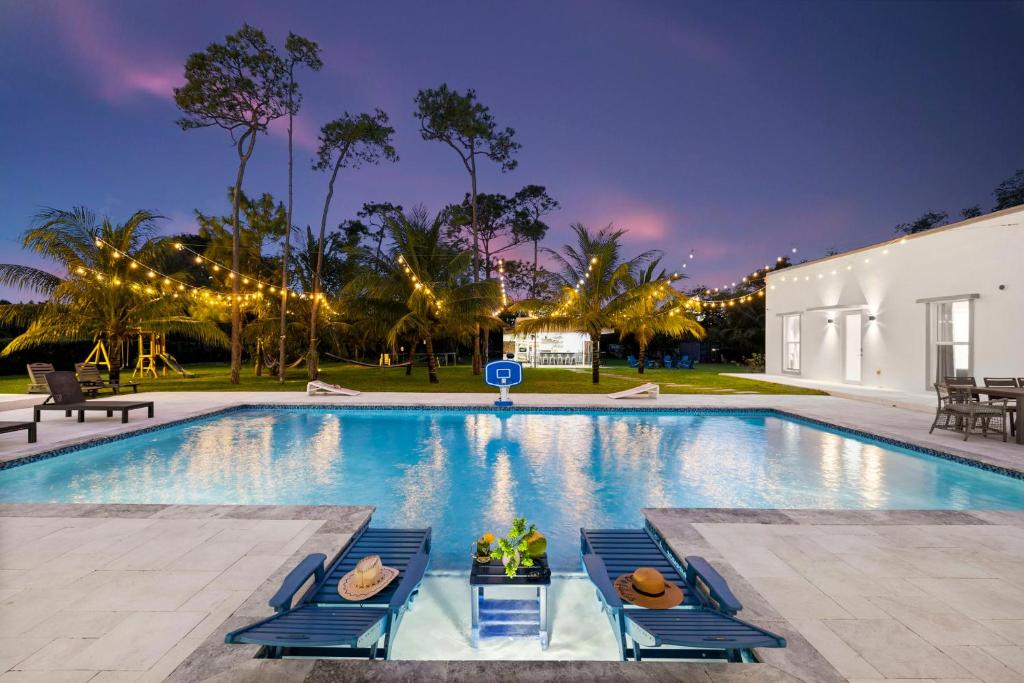 a swimming pool with blue chairs and a house at The White House of Miami Perfect for Families Ω Friendly Close to Miami Beaches and the Keys West in Princeton