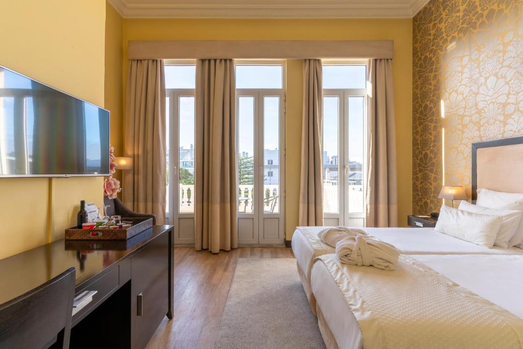 a hotel room with a large bed and a television at Hotel Inglaterra - Charme & Boutique in Estoril