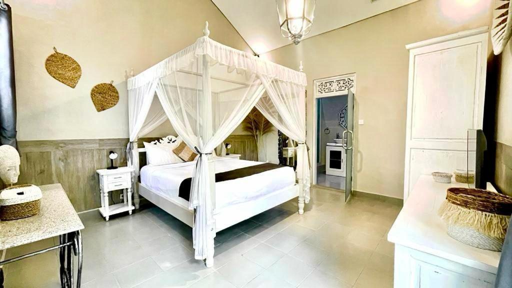 1 dormitorio con 1 cama blanca con dosel en Frangipani Villa Seminyak, en Seminyak